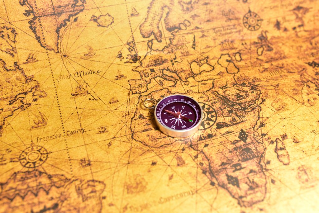 Compass on map. Tourist compass for orientation on the terrain. Magnetic declination alculator. Historical explorer help. Map reading and land navigation concept. Orient on maps